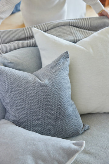 Gray herringbone and cream striped throw pillow covers arranged on a gray sofa.6