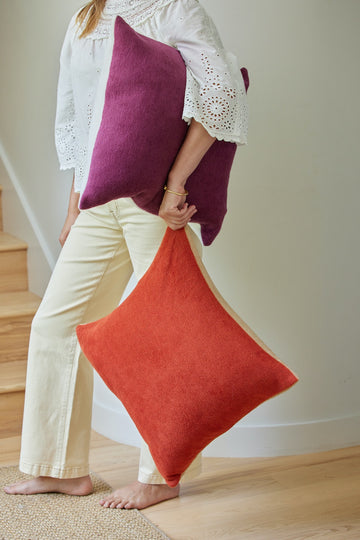 Burgundy and coral solid throw pillow covers held by a person wearing a white lace top.2