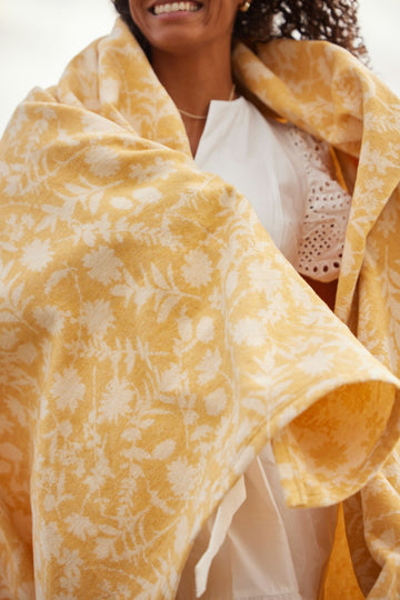 Yellow and cream daffodil-patterned lightweight blanket draped over a person's shoulders.5