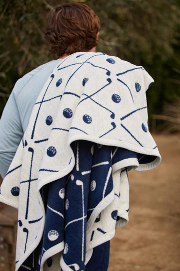 Cream and navy reversible blanket with golf ball and club line patterns draped over person's shoulders.6