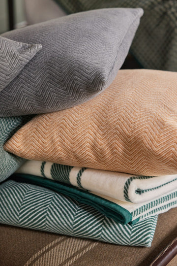 Stacked throw pillow covers in gray, peach, cream with stripes, and teal, all featuring herringbone weave pattern.5