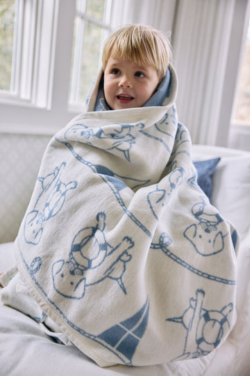 Toddler wrapped in cream and blue blanket with sailor dog pattern and rope design.4