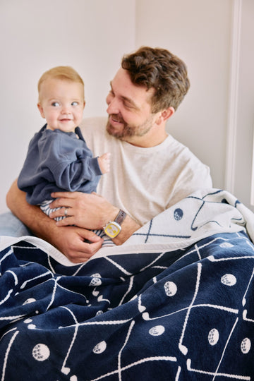 Navy and cream blanket with golf ball and club line pattern draped over adult and toddler.3