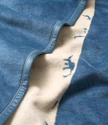 Blue and cream blanket with map design, folded to show stitched edge detail.5