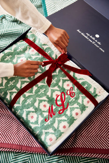Cream and green floral blanket with red embroidered monogram tied with red ribbon in gift box.7