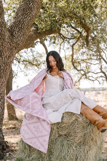 Pink floral lightweight blanket draped over a woman's shoulders while sitting under a tree.6