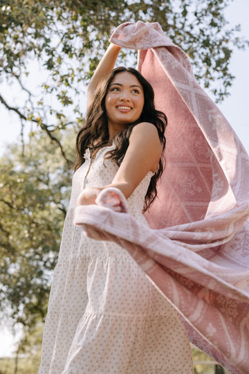 Pink floral lightweight blanket with geometric pattern draped around a woman outdoors.2