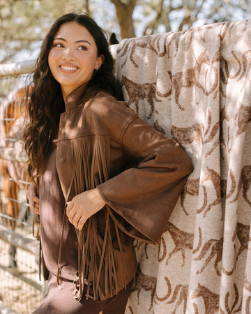 Tan and brown horse-patterned lightweight blanket displayed outdoors with fringe detailing.5