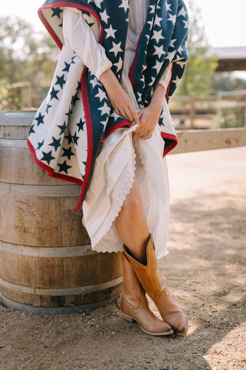 Navy and white star-patterned blanket with red trim, draped over person's shoulders outdoors.4