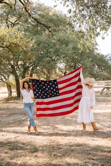 Red, white, and blue American flag blanket with stars and stripes held by two women outdoors.2