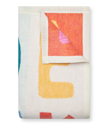 Cream blanket with colorful ABC letters in red, yellow, and teal, partially folded to show texture and design details.5