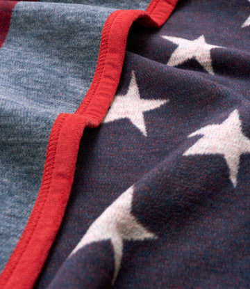 Folded blanket with white stars on dark blue and red binding along the edge.3