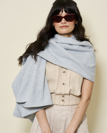 Light blue herringbone patterned shawl draped over woman's shoulders.1