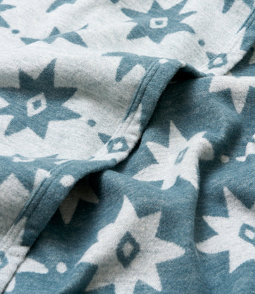 Lightweight blanket in teal and cream with an allover geometric star and diamond pattern.4