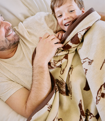 Cream and brown blanket with bird dog pattern, shown wrapped around adult and child on couch.4