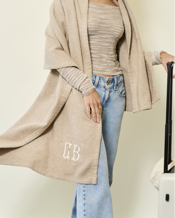 Beige herringbone shawl with monogram draped over model wearing striped top and light wash jeans.9