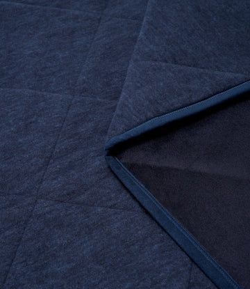 Navy blue outdoor blanket with textured weave and dark binding along the folded edge.7