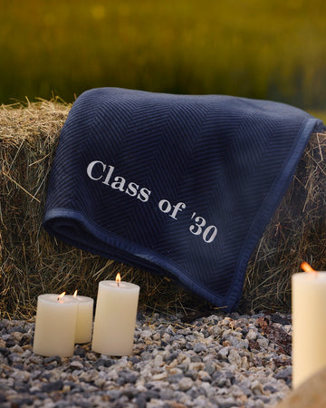 Navy blue blanket with herringbone pattern and "Class of '30" embroidered in white text, draped over hay.6