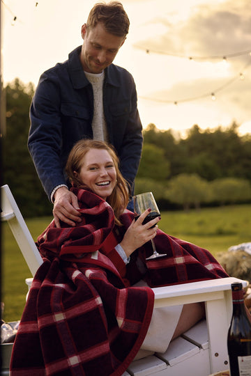Red and cream plaid blanket draped over woman seated outdoors.5