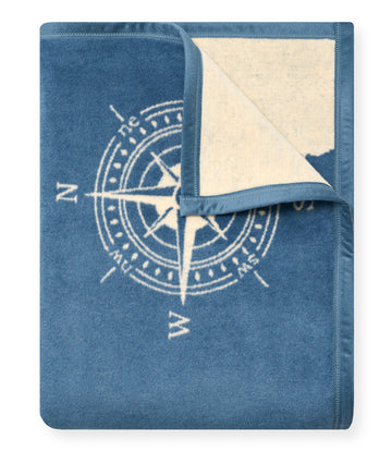 Blue fleece blanket with compass rose design and cream-colored reverse side, folded corner visible.3