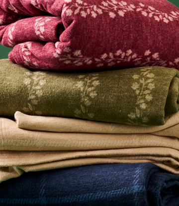 Stacked lightweight blankets in burgundy, olive, tan, and navy with leafy jacquard patterns.5