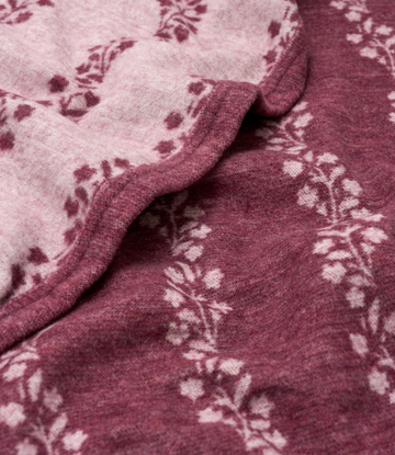 Lightweight blanket in burgundy and mauve with climbing fig vine print, shown folded with visible fabric texture.4