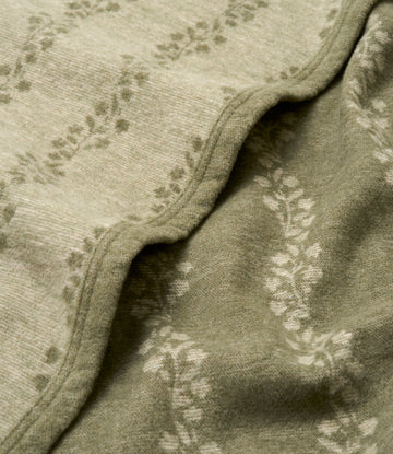 Sage green lightweight blanket with climbing ivy leaf jacquard pattern and bound edge detail.5