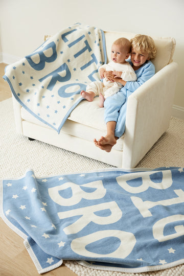 Blue and cream midi blanket with "BIG BRO" text and star pattern, draped over chair with two children.4