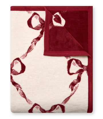 Burgundy and cream blanket with red bow pattern throughout and burgundy binding on edges.