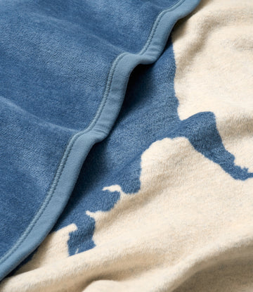 Blue fleece blanket with cream binding and dark blue map design on cream background, showing edge detail.3