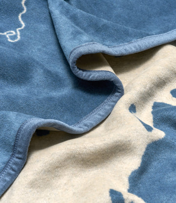 Blue and cream fleece blanket with Door County map outline and rolled edge detail.3