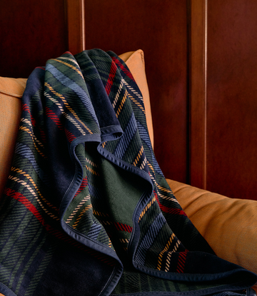 Tartan blanket with navy, green, red, and gold plaid pattern draped over a tan chair.4