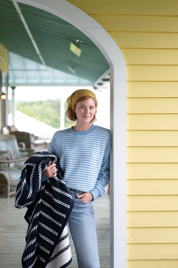 Woman holding black and white striped knot blanket with diagonal pattern on porch.2