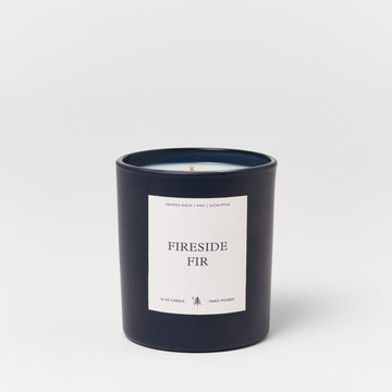Dark navy cylindrical candle with cream label reading "Fireside Fir," containing a single wooden wick and 15 oz of wax.3