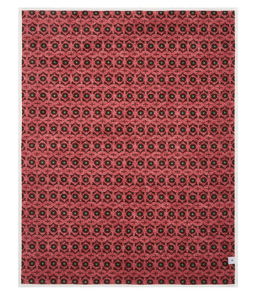 Coral-pink blanket with repeating dark geometric floral pattern throughout.12