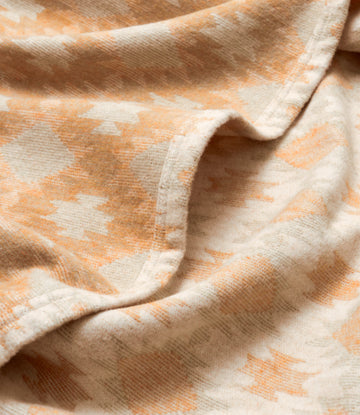 Lightweight blanket with peach and cream geometric pattern and ribbed texture throughout.4
