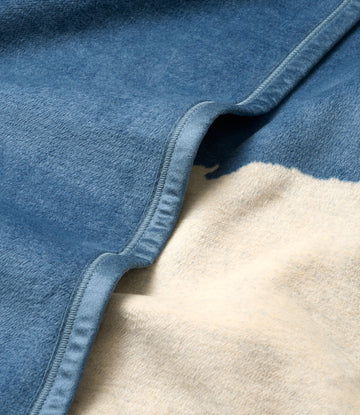 Blue and cream fleece blanket with stitched edge binding detail showing two-layer construction.3
