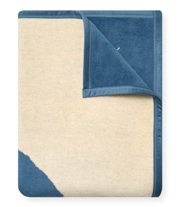 Folded blanket with cream and blue-gray colorblock design, corner partially unfolded to show both sides.4