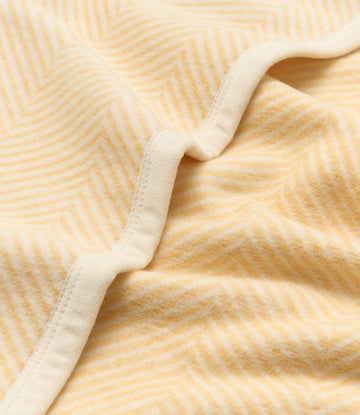 Butter yellow blanket with herringbone weave pattern and white binding edge, folded to show texture.4