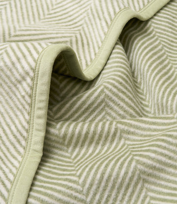 Green and cream herringbone patterned blanket with bound edges, shown folded to display the woven texture.5