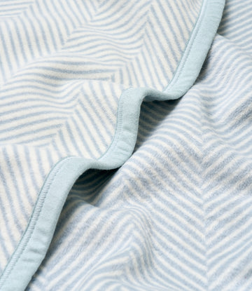 Light blue and white herringbone patterned blanket with bound edge detail.5