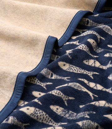 Navy blue blanket with cream fish pattern and navy binding, layered with a tan blanket.6