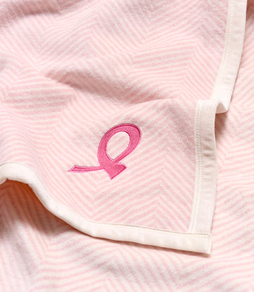 Light pink herringbone fabric with embroidered magenta ribbon logo and white trim detail.3