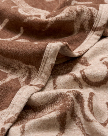 Tan and brown woven blanket with horse head pattern and bound edge detail.3