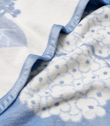 Blue and white blanket with hydrangea flower pattern and reinforced binding along the edge.6
