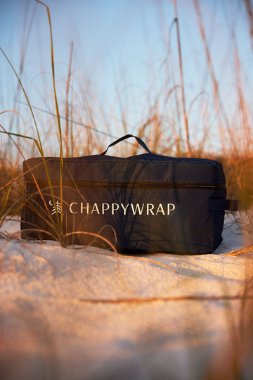 Black Chappywrap outdoor blanket in carry bag on sand with beach grass in background.5