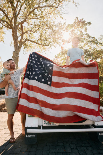 Red, white, and blue American flag blanket with stars and stripes, held by a man and child outdoors.6