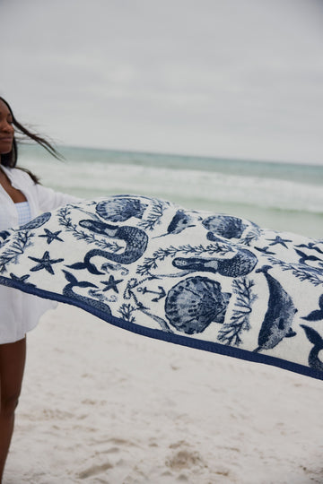 Cream and navy blanket with sea creature and starfish print displayed on a beach.5