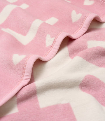Pink fleece mini blanket with white heart pattern and pink binding along the edge.4