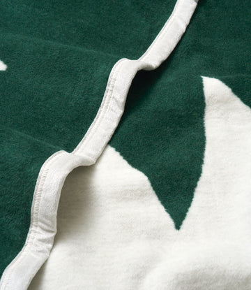 Green and white blanket with white binding edge and pine tree design.3